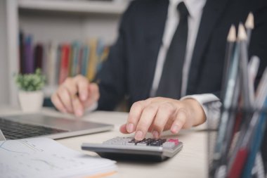 Ofisteki veri hesap makinesini hesaplayan muhasebeci ya da finans analisti. İş denetimi, şirket bütçesi ve dizüstü bilgisayarlı kar analizi ve yatırım planlama belgeleri üzerine profesyonel çalışma.