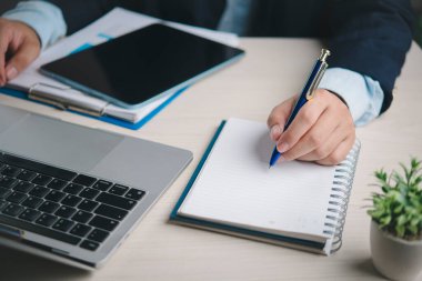 İş adamı, ofis masasındaki dizüstü bilgisayarına proje yönetimi verimlilik organizasyonu kavramını planlamak için dizüstü bilgisayarla notlar yazar..