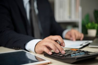 Muhasebeci, faturalandırma vergisi hazırlama finansal analiz doğruluğu kavramını faturalandırmak için evrak işleri ve laptopun yanındaki hesap makinesini kullanarak rakamlar üzerinde çalışır..