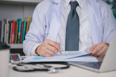 Doktor, sağlık uzmanı EHR 'ı, EMR' yi korumak, uyum sağlamak ve hasta bakımını düzene sokmak için klinikteki dosyaları ve formları kontrol ediyor. konsept kayıt ve kalite.