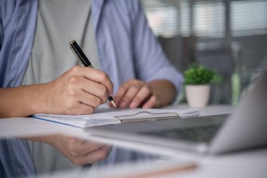 Yakın çekim adamı belge panosuna notlar yazıyor. Öğrenci çalışması, çalışan çalışma masası. Raporu kontrol et, başvuru formunu doldur, sözleşmeyi imzala, evrakları hazırla, planla, listele.