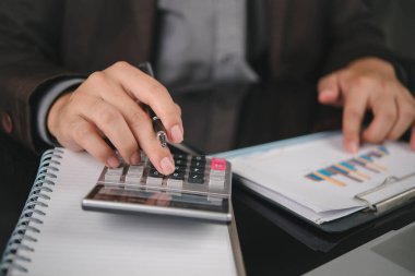 Muhasebeci el ele tutuşma kalemi, hesap makinesi, finansal veri tablosu. İş finans konsepti. Ofis masasında çalışan adam, raporu analiz et, bütçeyi planla, şirket denetimi, çek..