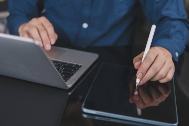 Uzaktan kumandayla ve dijital tabletle çalışan bir adam. Öğrenci internetten öğreniyor, Stylus 'la notlar yazıyor. İşletme verimliliği ve çoklu görev alanları için modern teknoloji.