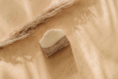 El yapımı sabun ve otlar. Bej arka planda güneş gölgesi. Sıfır atık, çevre dostu kozmetik konsepti. Vintage renk filtresi