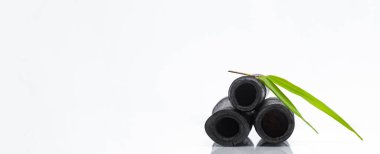 Bambu kömür kömürü su filtresi çubukları ve yeşil yaprak. Doğal bambu kömürü musluk suyunu tazeleyen güçlü bir arıtıcıdır. Deodorizasyon, hava filtresi ve dekor konsepti