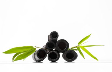 Bambu kömür kömürü su filtresi çubukları ve yeşil yaprak. Doğal bambu kömürü musluk suyunu tazeleyen güçlü bir arıtıcıdır. Deodorizasyon, hava filtresi ve dekor konsepti