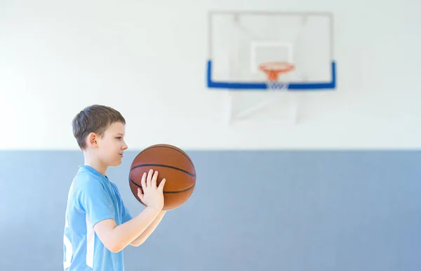 School kid playing basketball in a physical education lesson. Safe back to school during pandemic concept