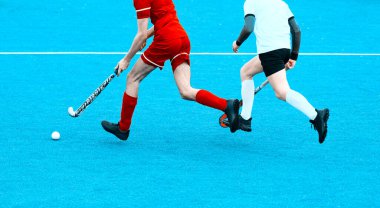 İki çim hokeyi oyuncusu, yeşil çimlerde yoğun bir maç sırasında orta sahada top için kavga ediyorlar. Profesyonel spor konsepti. Vintage renk filtresi