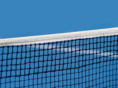 Mavi raket, tenis ağı ve sert kort. Profesyonel spor ve tenis yarışması konsepti