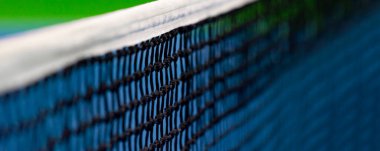 Mavi raket, tenis ağı ve sert kort. Profesyonel spor ve tenis yarışması konsepti