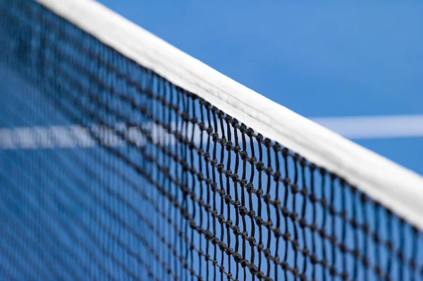 Mavi raket, tenis ağı ve sert kort. Profesyonel spor ve tenis yarışması konsepti