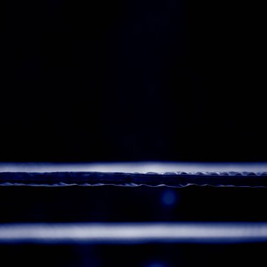 Bulanık spot ışıklarıyla boks ringinin ipleri. Profesyonel spor konsepti. Mavi renk filtresi