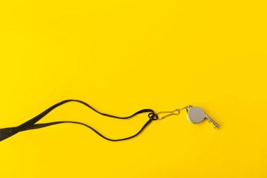 Sarı arka planda spor düdüğü. Kavram - spor müsabakası, hakem, istatistik, meydan okuma. Basketbol, hentbol, futsal, voleybol, futbol, futbol, futbol ve hokey hakemi düdüğü.