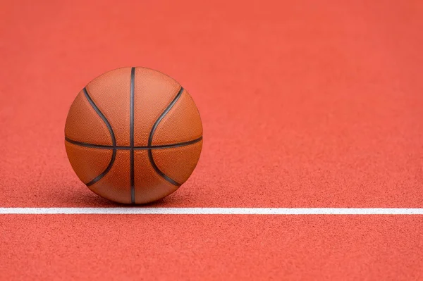 Spor salonunun kahverengi sahasında turuncu basketbol. Sokak basketbolu