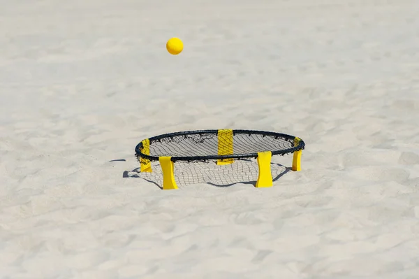 Spike ball game with yellow ball on sand. Summer game concept