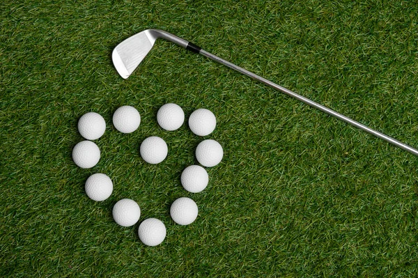 Golf sopası ve toplar kalp şeklinde dizilmiş.