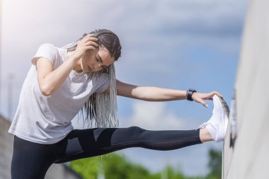 Afrika örgülü bir kadın şehir caddesinde müzik dinliyor. Sokak ve müzik sporları