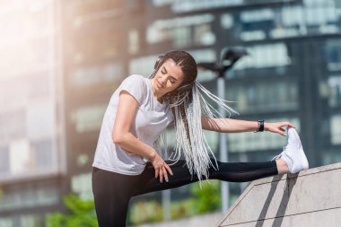 Afrika örgülü bir kadın şehir caddesinde müzik dinliyor. Sokak ve müzik sporları