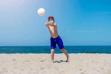 Genç çocuk plajda voleybol oynuyor. Yaz sporu.