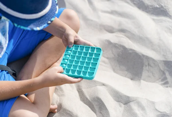 Blauwe Speelgoed Antistress Handen Van Een Jongen Achtergrond Van Zand — Stockfoto