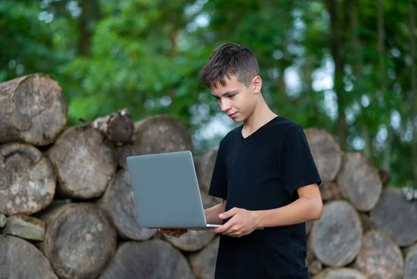 Boy with laptop in forest. Kid have online web lesson or class on computer at nature, green class. Back to school concept.