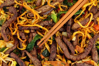 Biftek ve yumurtalı şehriye, sebze ve ahşap yemek çubuklarıyla kızartılır.