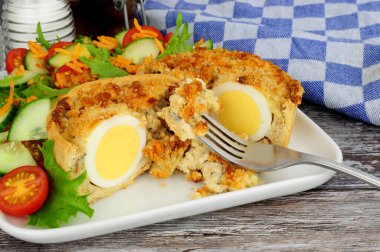 İskoç yumurtalı kiş, kıtır hamurlu börek ve domuz sosisi ve taze salatayla kaplanmış yumurta.