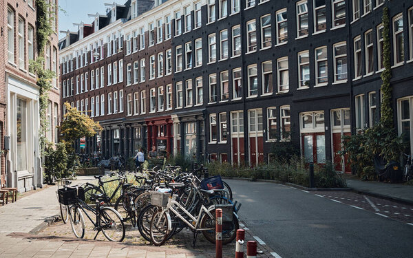 Amsterdam, Netherlands - 4 August, 2019: a lot of bicycle parking in front of colorful building in Amsterdam city with