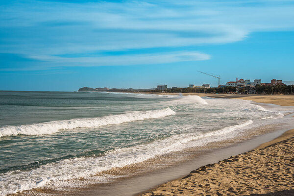 Волны катятся к волнам у причала Сокчо, Южная Корея, с красными маяками под ясным голубым небом.