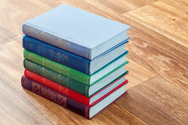 Prolhaný pestrobarevným knihy na dřevěný stůl. — Stock fotografie