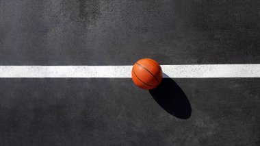 orange striped basketball ball stands on the white line marking the playing field with asphalt tarmac, sports object lit by sun light on playground top view with copy space, nobody. clipart