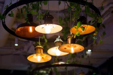 Edison ampulleri olan yuvarlak kolyeli tavan arası fenerleri karanlık restoranın içinde sıcak ışıklarla parlıyor, asılan lambalara yakın, kimse yok. Aydınlatma donanımlı çatı katı tarzı restoran..