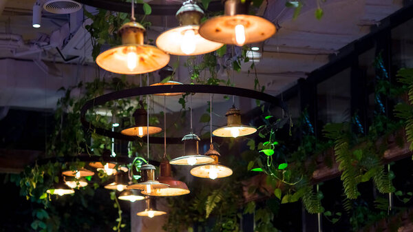 several round pendant retro loft style lanterns with edison bulbs shine with warm light in interior of dark restaurant, closeup of hanging lamps, nobody. loft-style restaurant with lighting fixtures.