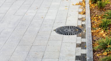 Rögar kapağı, Black Metal kafes kaplaması. Şehir parkının kaldırımında granit gri fayanslarla döşenmiş sonbahar mevsimi, düşmüş sarı yapraklarla yakın plan manzaralı, kimse yok..