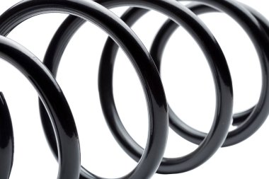 Siyah çelik araba süspansiyon sistemi yedek parçalarında bobin yayı, beyaz arka planda izole edilmiş yedek parçayı kapat.