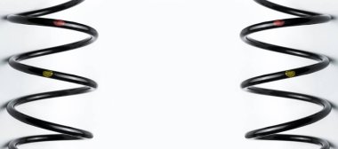 Siyah bobin yayı, araba süspansiyonu için dayanıklı çelikten yapılmış. Yakın plan, yedekte yedek parça, beyaz arkaplanda da fotokopi alanı, kimse yok..