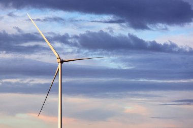 Rüzgâr türbini pervaneli kule yenilenebilir yeşil enerji üretimi bulutlu gökyüzüne karşı, elektrik üretmek için bir çiftliğin temasının arka planı.