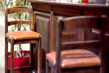 Kahverengi tahta bar taburesi, yüksek bacaklı, deri koltuk minderli retro tarzı, koltuk detaylarını yakın plan, kimse.