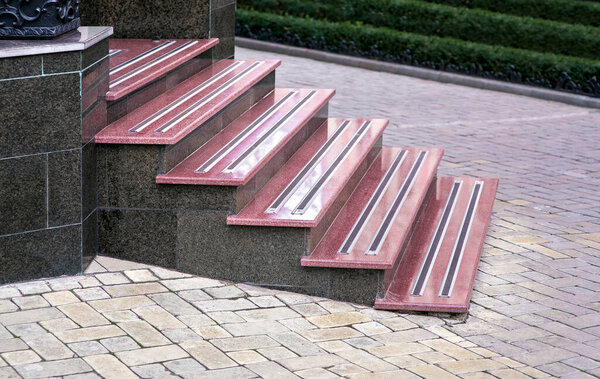 гранитная лестница с мраморными ступенями и нескользящими резиновыми полосками возле пешеходной дорожки с изгородью из зеленых кустов, городской пейзаж европейского города с классической архитектурой, никто.