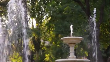Yeşil ağaçlı bir parkta akan su fıskiyeleri olan mimari taş fıskiyesi, hiç kimse..