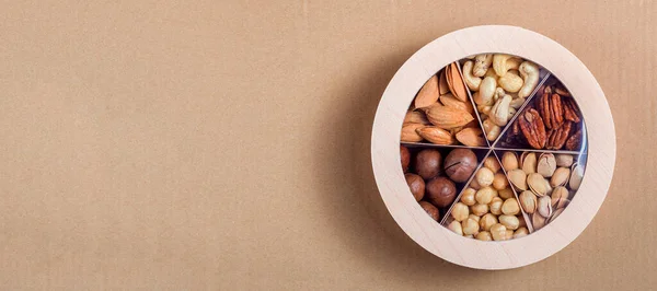 木制圆形礼品盒 装有一套不同类型的坚果 供素食主义者在纸上健康饮食生态工艺背景图与复印空间 没有人 — 图库照片