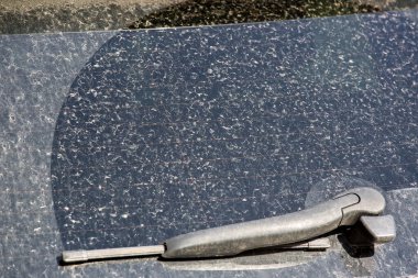 Silecekleri bataklıktan gelen kuru toz tabakasıyla kaplı kirli bir arabanın arka camı. Güneşli bir günde off-road yolculuğundan sonra bir aracın arka görüntüsü.