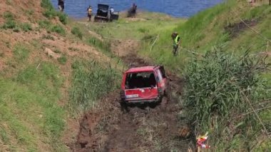 ODESSA, UKRAINE - Jule 03, 2021: Suv Mitsubishi Pajero yamacındaki çamurlu bir bataklıkta dört tekerden çekişli kırmızı çamurlu bir araba sürüyor.