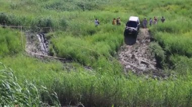 ODESSA, UKRAINE - Jule 03, 2021: Yağmur ormanlarına meydan okuma kirli siyah Suzuki Jimny bir hayatta kalma yarışması için sazlıkların arasındaki kaygan bir bataklıkta at sürüyor.