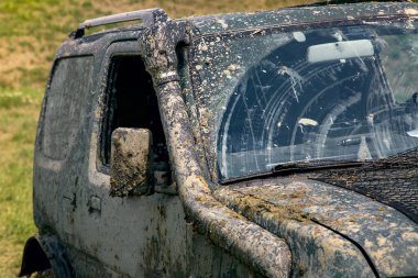 Güneşli bir havada off-road sürüşü sonucu kirli bir araba bataklıktan ön cam silecekleri silindi..