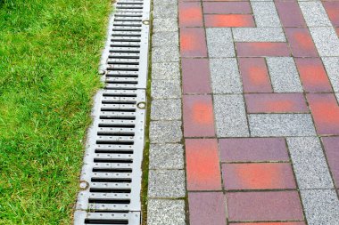 Yeşil çimenli taş kiremitlerin kaldırımındaki parktaki drenaj sistemi yağmur suyunun rendelenmesi, şehrin bahçe mühendisliği sistemlerini yakın plan yapmak, hiç kimse.