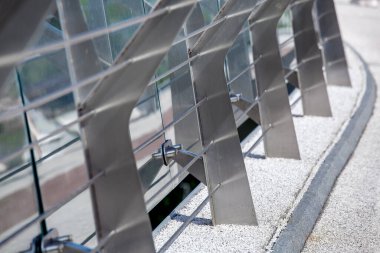 Metal virajlar çelik çubuklarla bağlanıyor. Yaya köprüsünde taş çakıl yolu ve cam bariyer var. İnşaatın güvenlik detayları için, kimse yok..