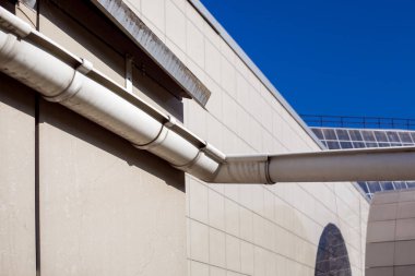 Güneşli bir günde dış cephede döşenmiş bir evin çatısındaki yağmur suyunu boşaltmak için kanalizasyon oluğu..