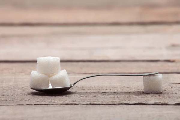 The refined sugar in cubes in a tea spoon