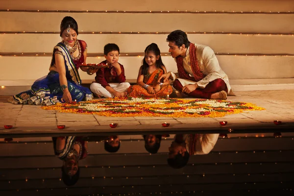 Family arranging diyas on rangoli — Stock Photo, Image